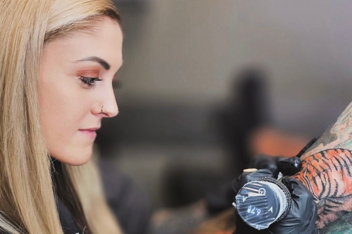 Tattoo artist concentrating on a client’s tattoo during a studio session